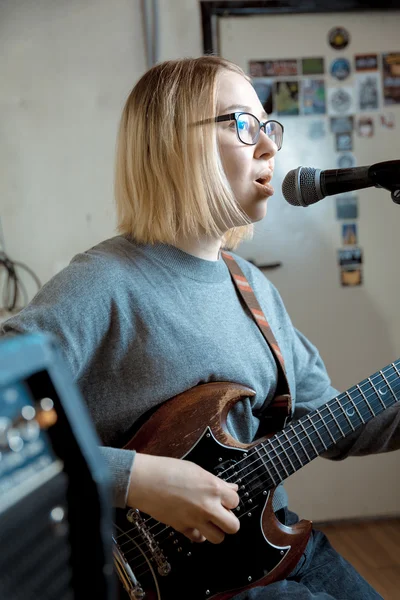 Young woman playing guitar and singing microphone