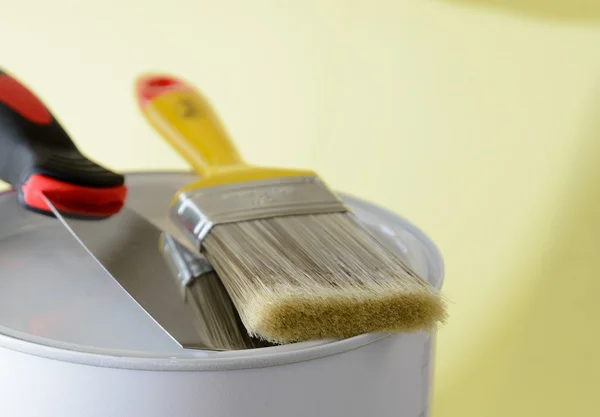 Paint brush with paint bucket and putty knife close up