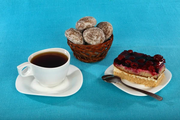 Cup of tea, cake and gingerbread on blue background