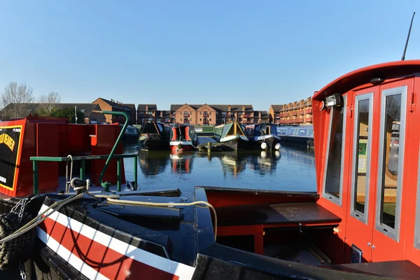 Narrow boats sit moored in frozen water at Staverton Marina