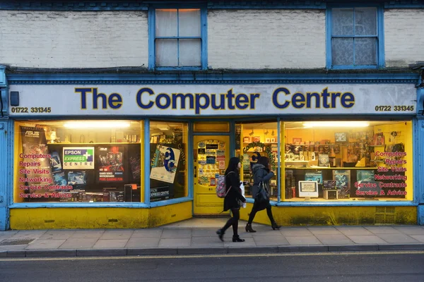 People walk past a computer shop on a city centre street.