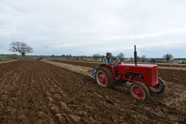 A tractor pulls a plough through a field