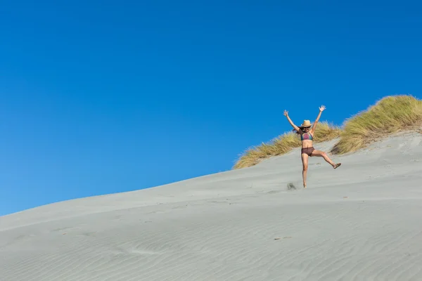 Woman traveler jumping on the sand dune