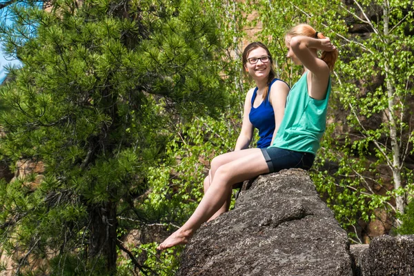 Two girls sitting on the edge of cliff