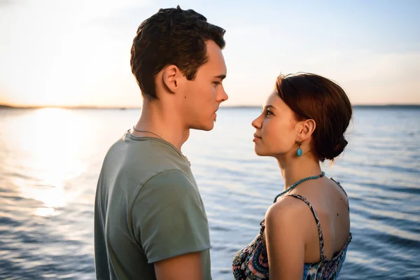 Happy beautiful couple walking and embracing on the beach of the sea at sunset