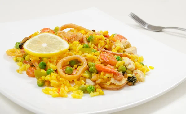 Paella with chicken and seafood on a white plate