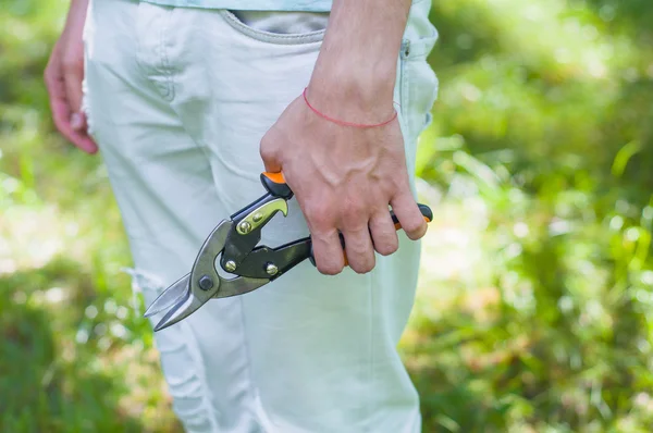 In left hand man holding a metal-cutting shears