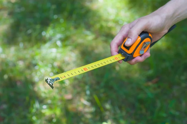 Builder hand measures the length. Hand holding a Self-retracting tape measure