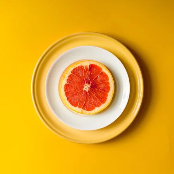 Red grapefruit slice on plate.