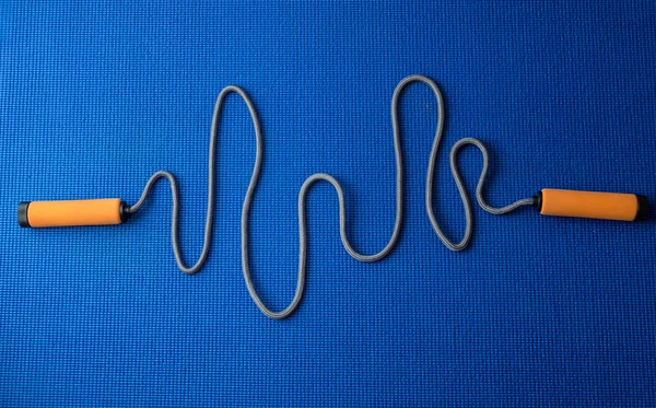 Cardiogram from jumping rope on blue yoga mat background