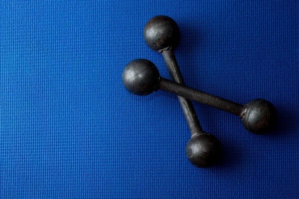 Retro iron grunge dumbbells on blue yoga mat background