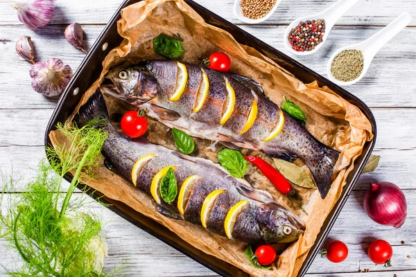 Raw trouts fish on a baking dish, top view