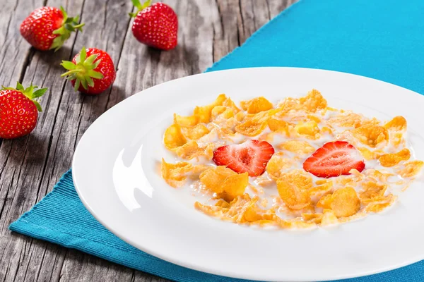 Corn flakes with milk and strawberries, close-up