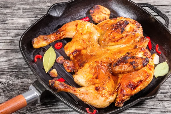 Grilled whole chicken in grill pan with garlic