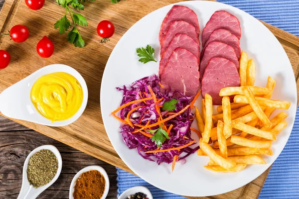 French fries and sliced smoked veal with cabbage salad