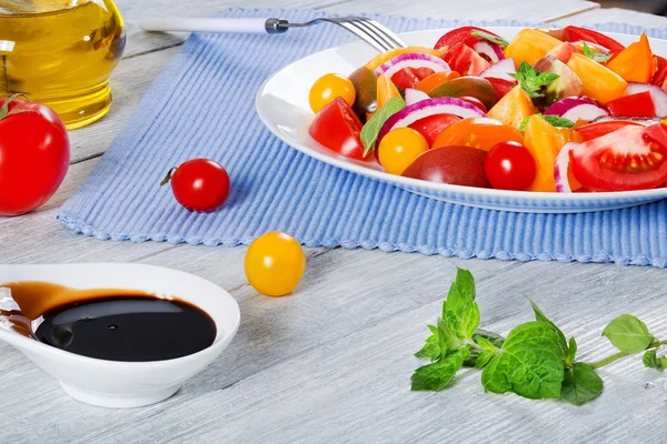 Tomato salad with red onion, mint leaves and olive oil