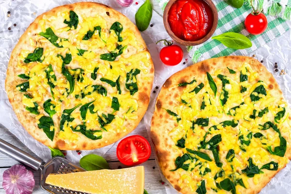 Vegetarian pizza with spinach leaves, cheese, top view