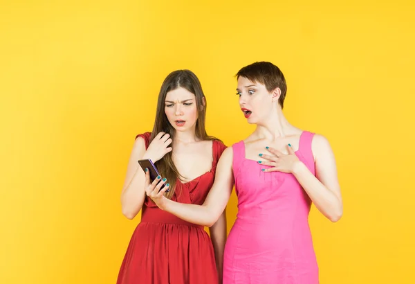 Two shocked women looking at mobile phone
