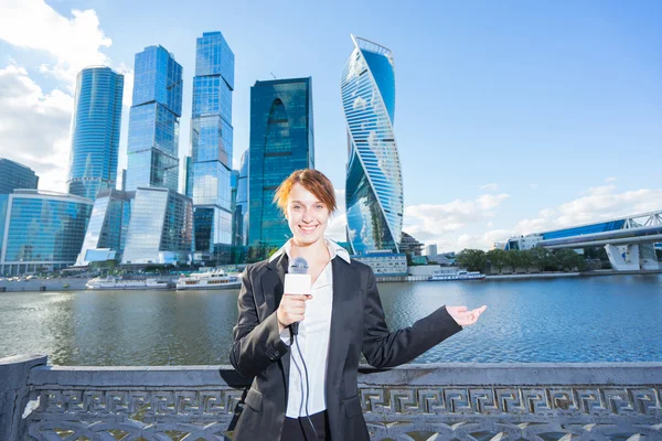 woman in business suit holding a microphone