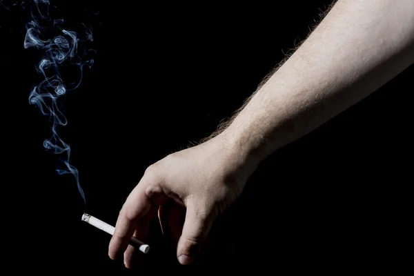 Man\'s Hand Holding a Smoking Cigarette on Black Background. Close up with White Cigarette Smoke.