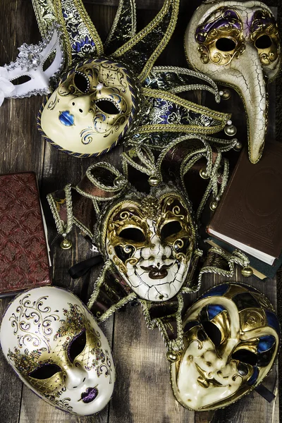 Venetian souvenir masks with vintage books on wooden surface