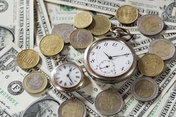 Time is money finance concept with old vintage clocks, dollar bills and euro coins