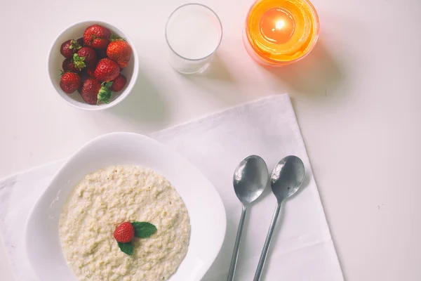 Oatmeal with milk. Porridge with milk. Cereals, delicious Breakfast, diet Breakfast. Candle. Strawberries, oatmeal and glass of milk. healthy eating cocept, selective focus. Top view.