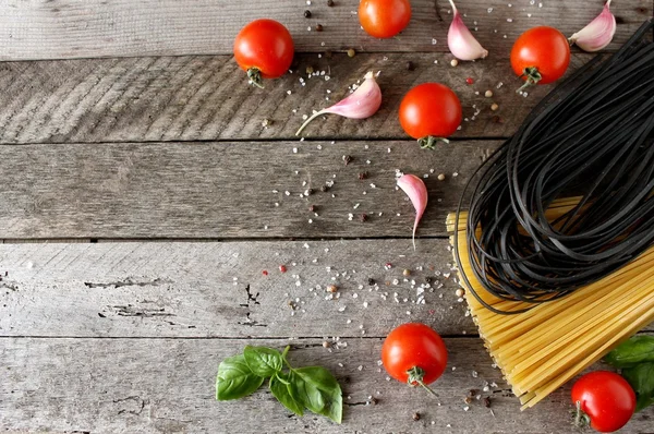 Ingredients for cooking pasta with tomato, black pasta, herbs, spices.