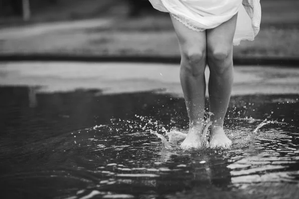 Woman walking barefoot through puddle