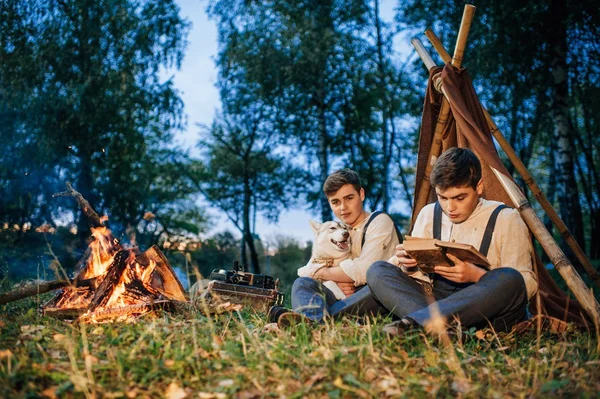 Two twin brothers sitting around a campfire