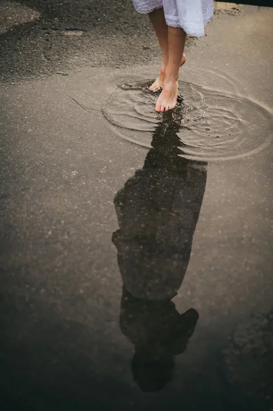 Woman walking barefoot through puddle