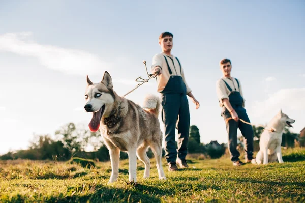 Two twin brothers with husky dogs