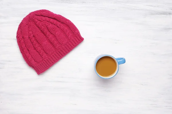 Top view of a cup of coffe and a knitted woman\'s hat