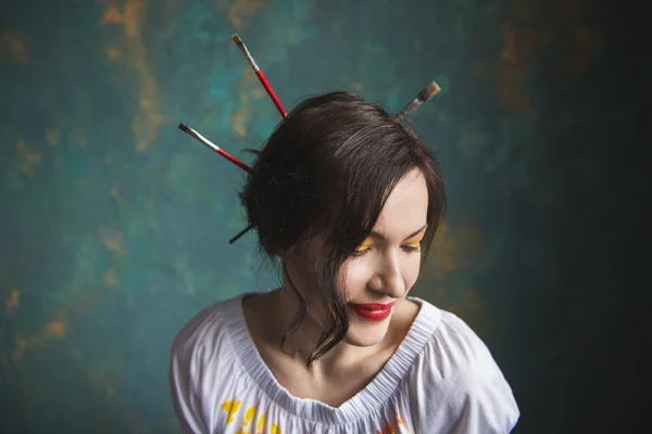 Young girl with brushes for painting in her hair