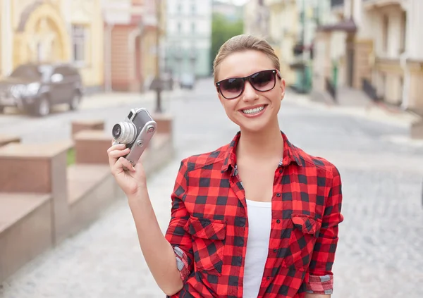 Beautiful woman holding camera and walking on the street.