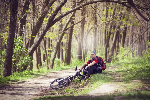 Biker resting under a tree with his bicycle near him