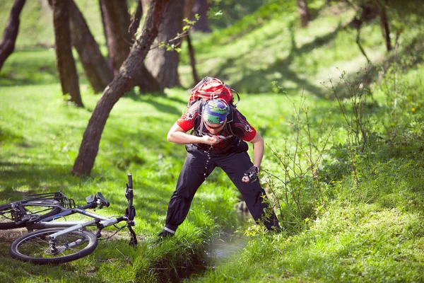 Mountain biker drinking water from a spring