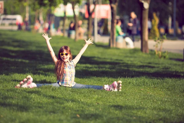 Girl wearing roller skates sitting on grass in the park