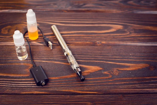 Electronic nicotine inhalator on  background ,bottles with liquids behind the inhalator