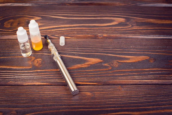 Electronic nicotine inhalator on  background ,bottles with liquids behind the inhalator