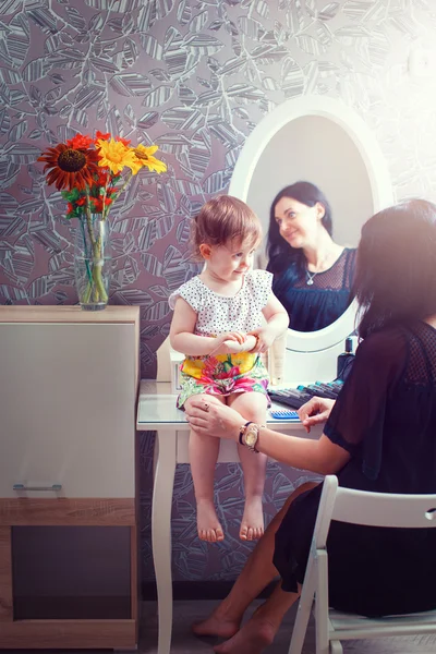 Mother and daughter sitting at dressing table at house.