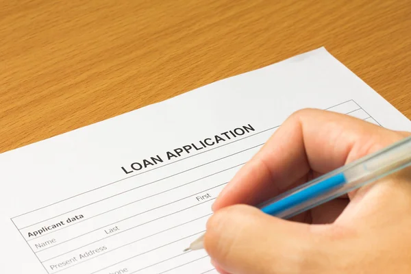 Hand held the pen to fill in loan application form
