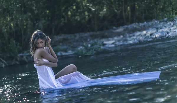 Blonde model in a river under water with long pink dress