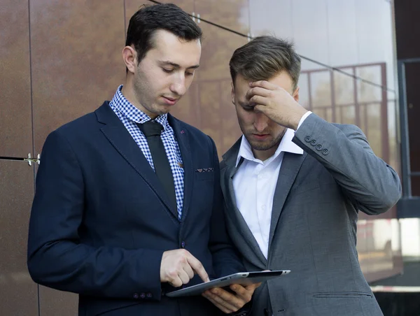 Two businessman looking at tablet. Failure in work.