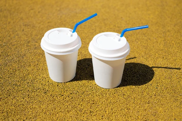 Two white coffee paper cups on a sunny day