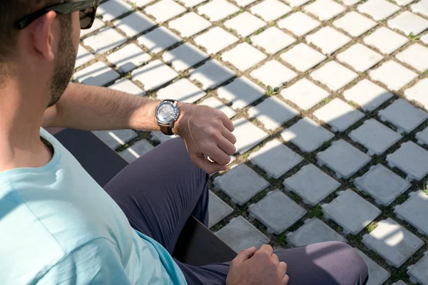 A man looks at his watch in the street