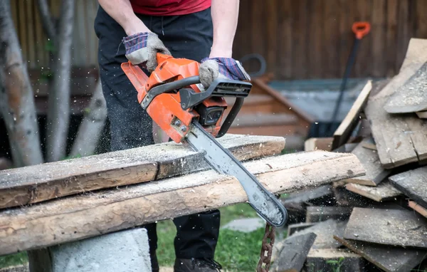 Man cuts chainsaw board outdoors