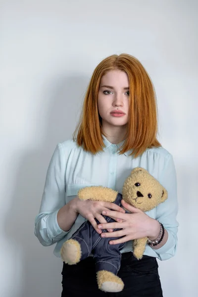 Girl standing with a teddy bear.