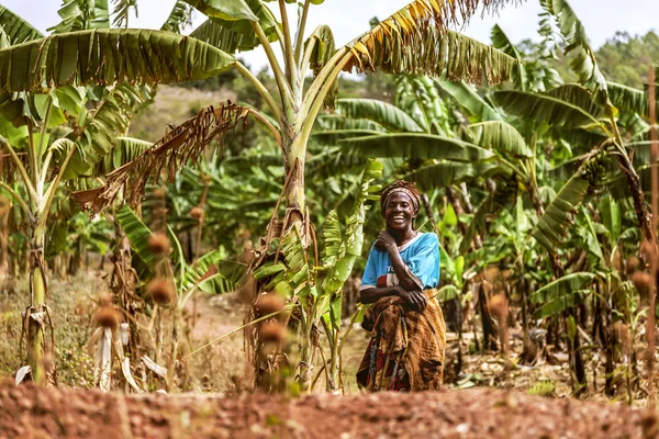 The woman between banana trees looking and laughing seems happy.