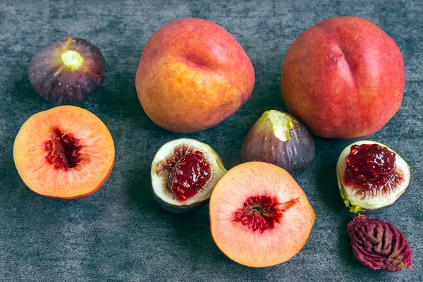 Colorful fresh fruits - figs and peaches on the dark background.